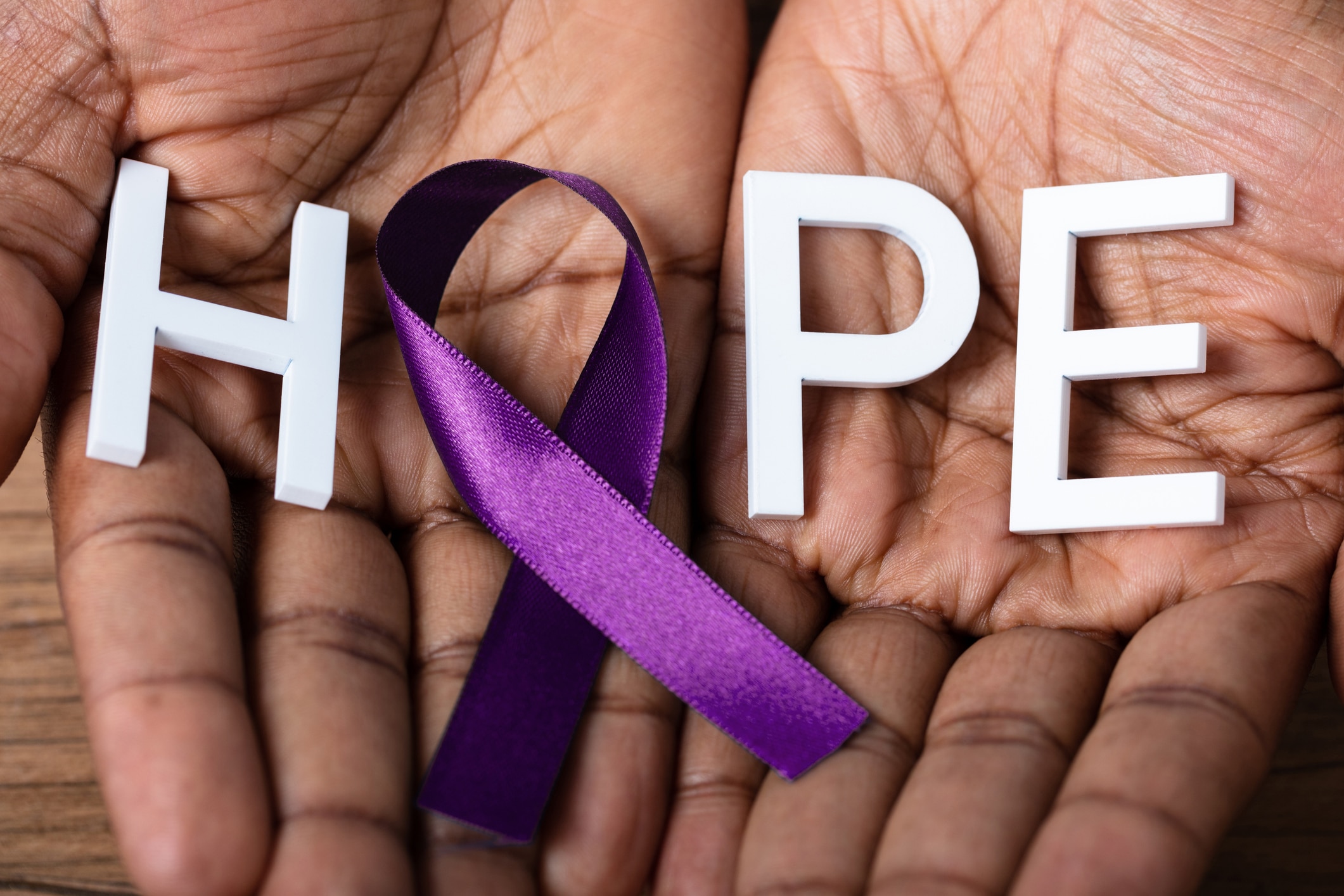Close-up Of A Person's Hand Holding Ribbon With Hope Text To Support Alzheimer's Disease Awareness