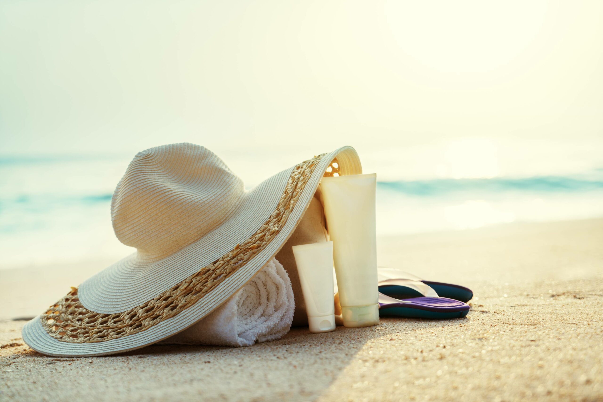 Sun lotion, hat with bag at the tropical beach