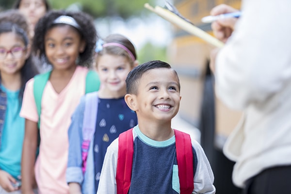 child smiling standing in front of the line at school