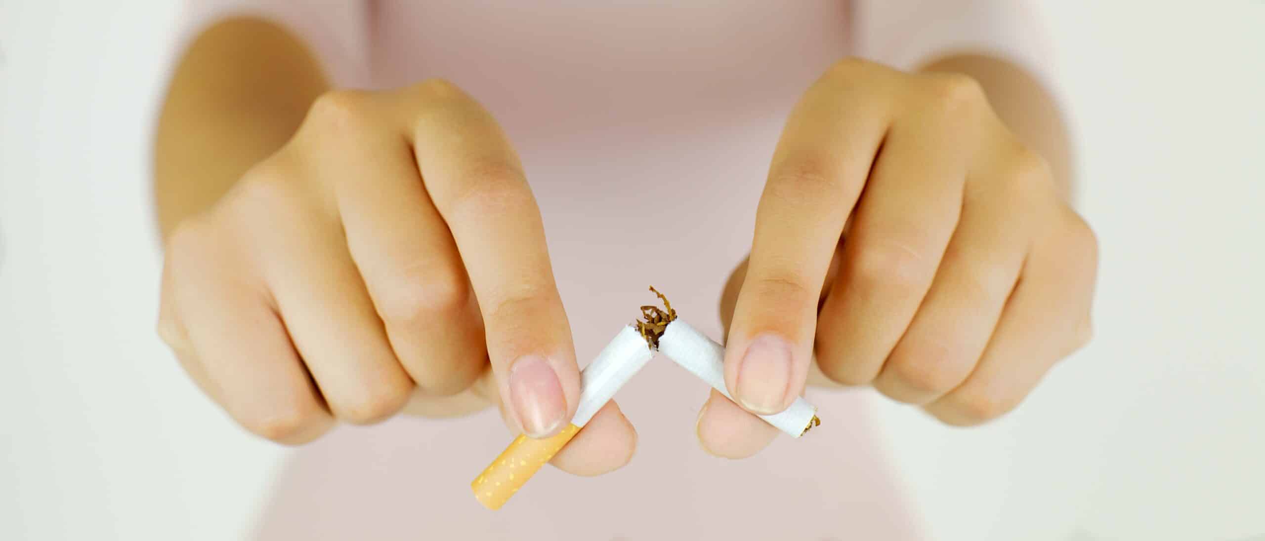 close up of woman breaking cigarette in half