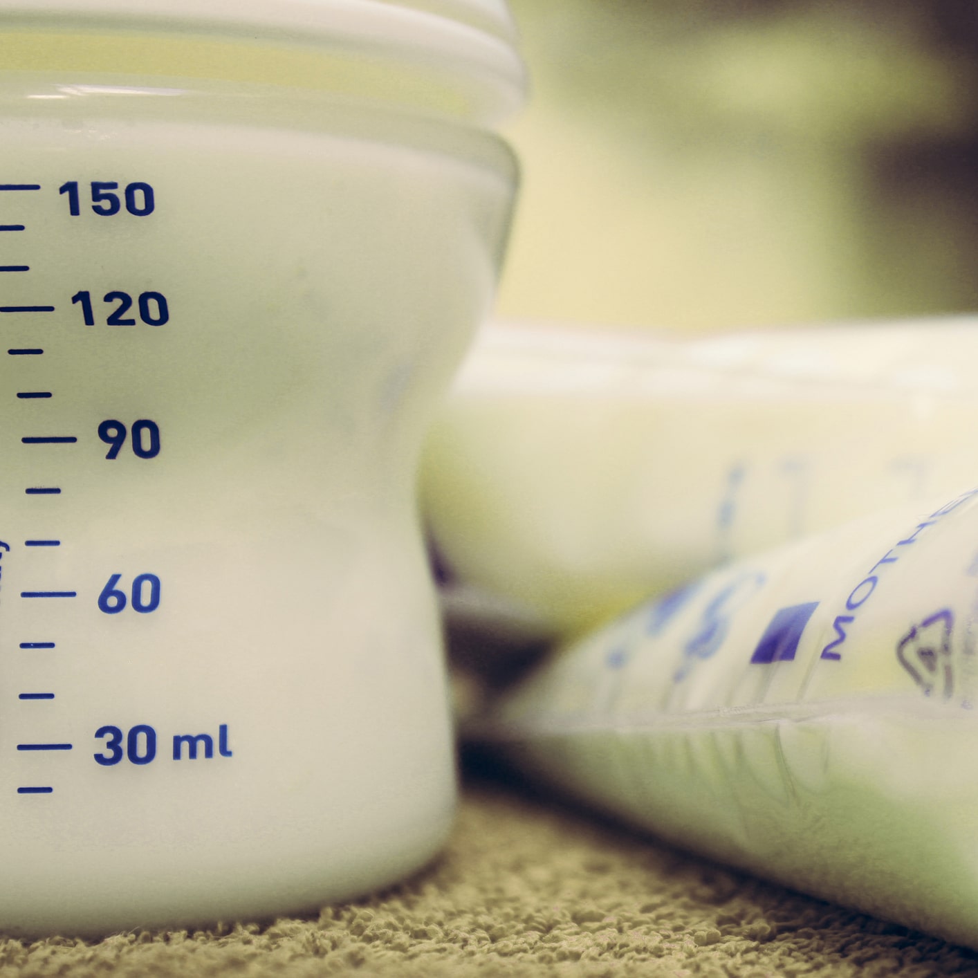 baby bottle filed with breast milk and storage bags with frozen breastmilk, breastfeeding concept