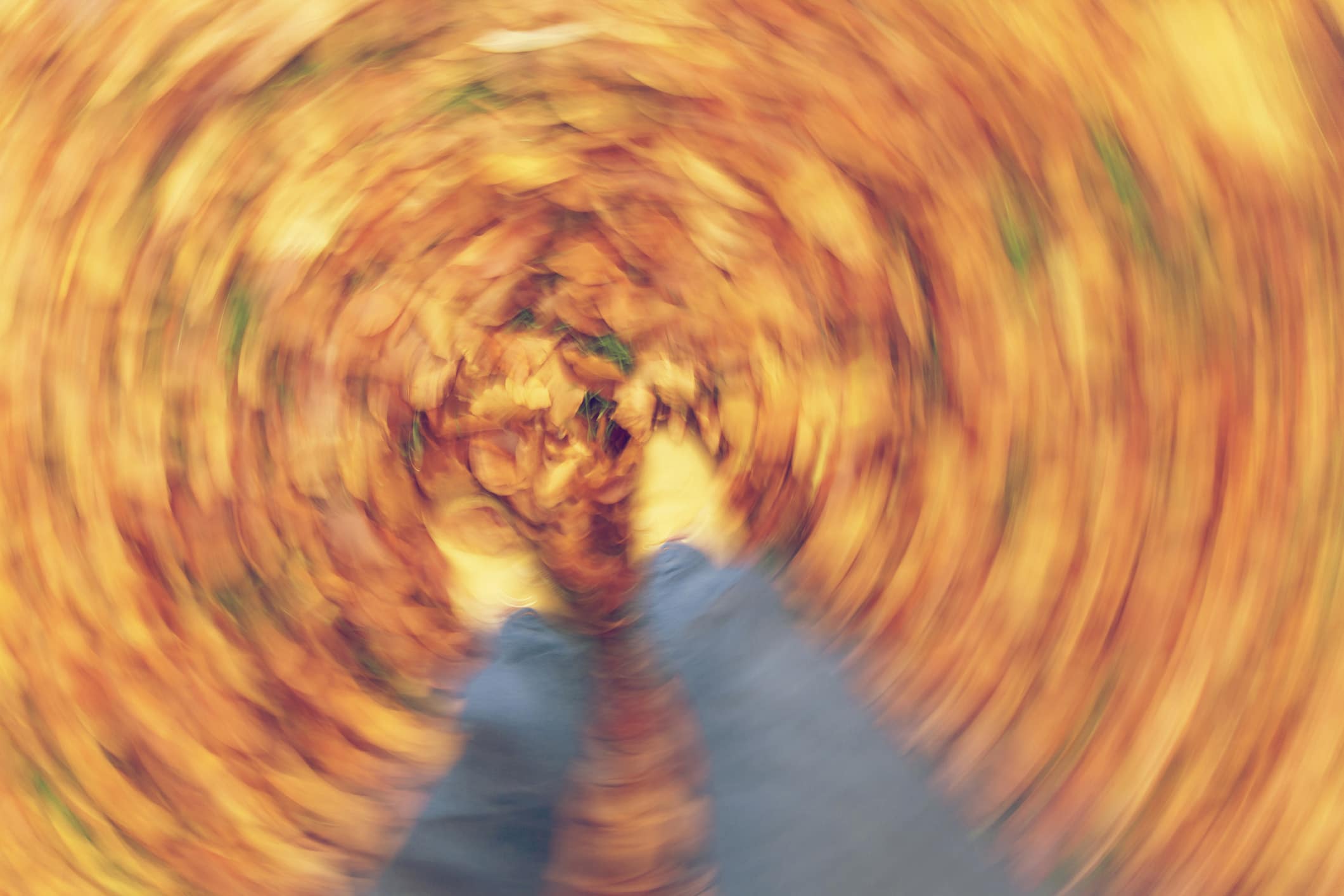 Motion blurred photograph of man or woman's feet walking through golden Fall or Autumn leaves