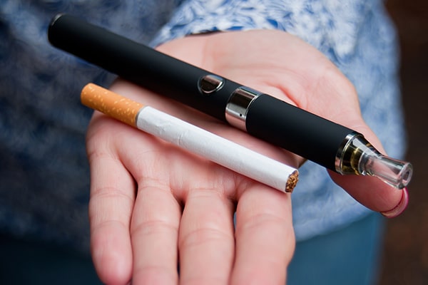 Close up of woman holding a cigarette and a e-cigarette