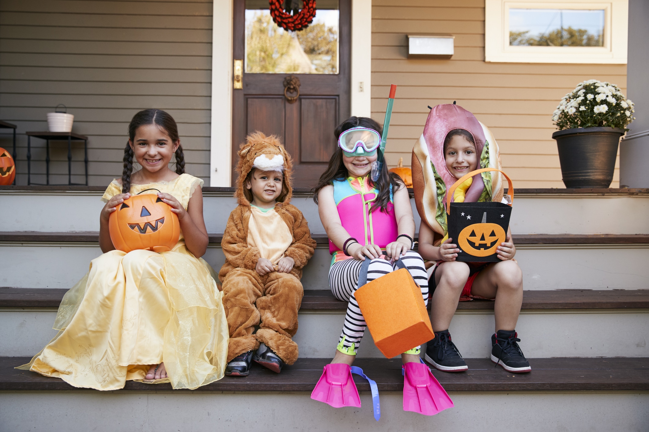 Children in costumes sitting down together with their candy buckets