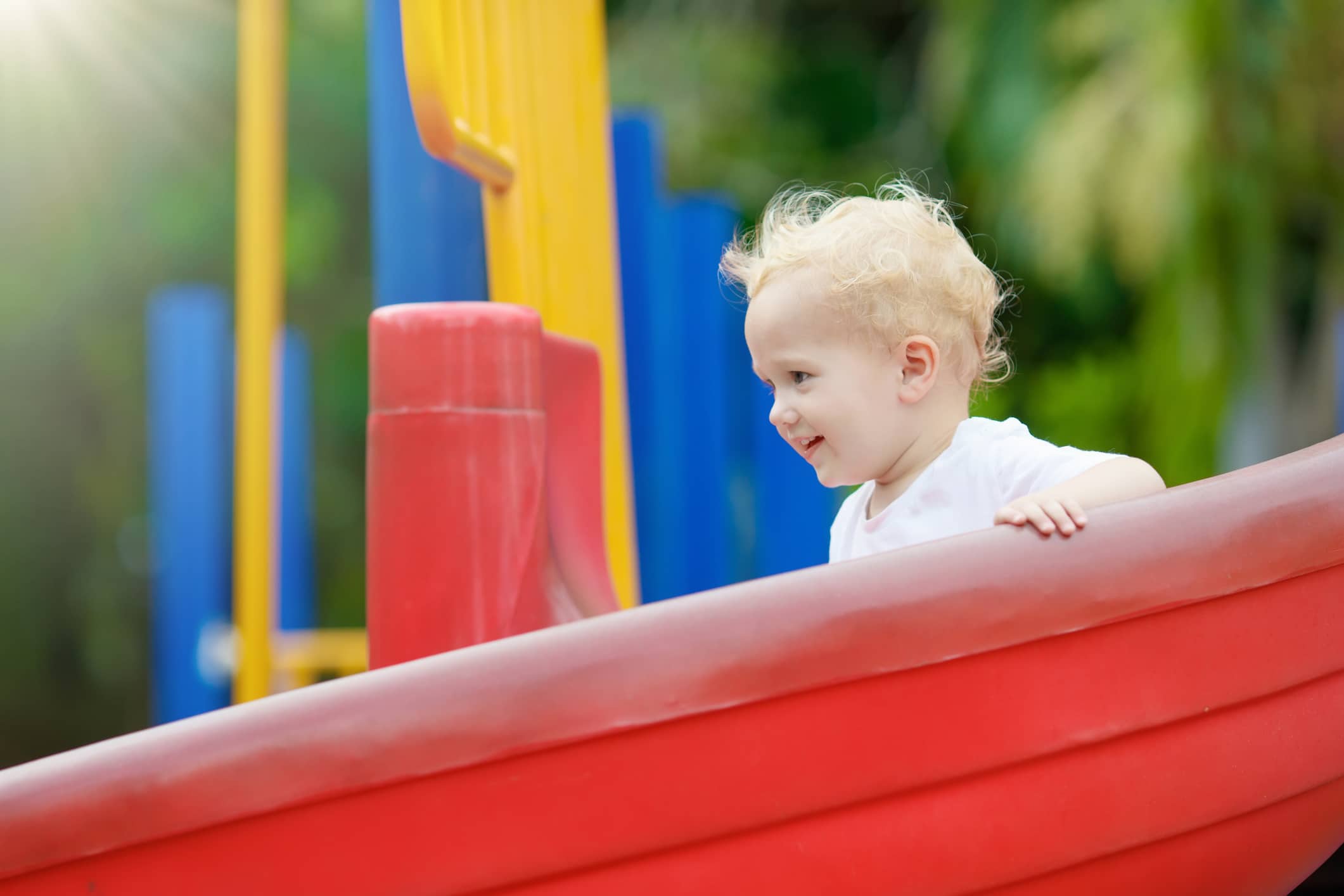 child at the playground sliding down red slide