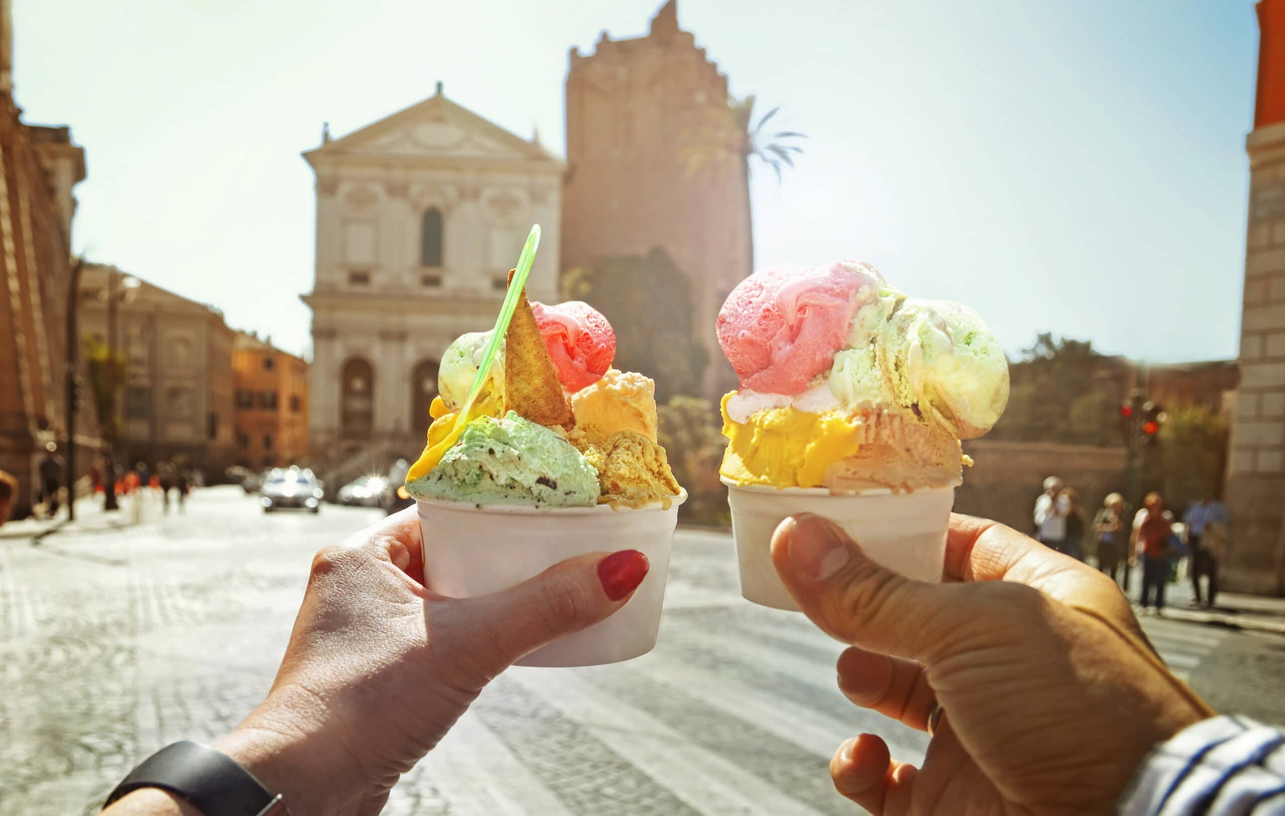 Couple with beautiful bright sweet Italian ice-cream with different flavors in the hands on the square in Rome , Italy