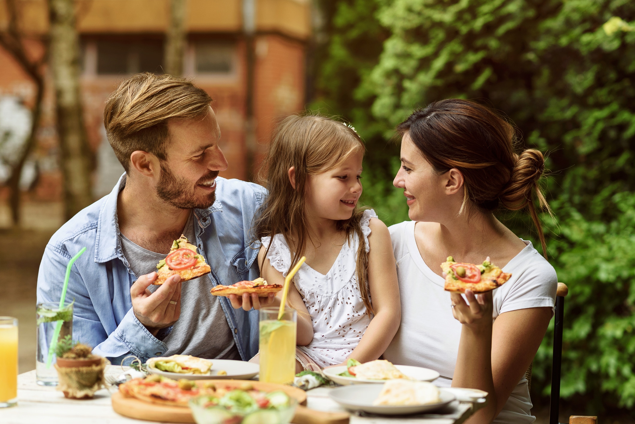 family of three eating pizza together and drinking lemonade