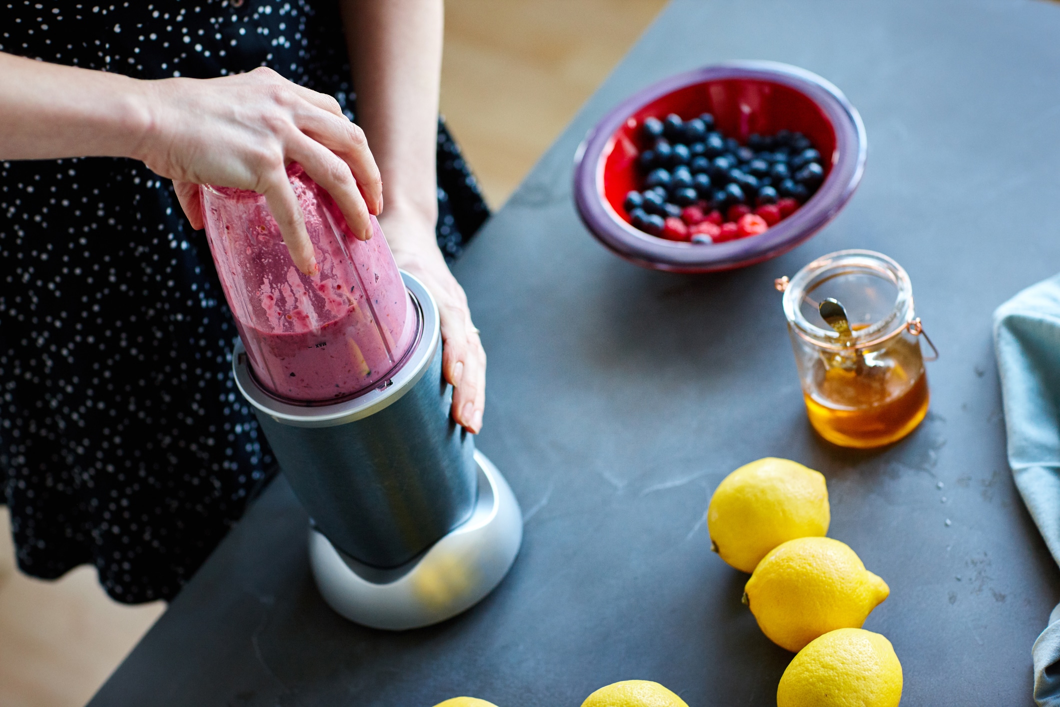woman picking up a smoothie with berries, honey, and lemon
