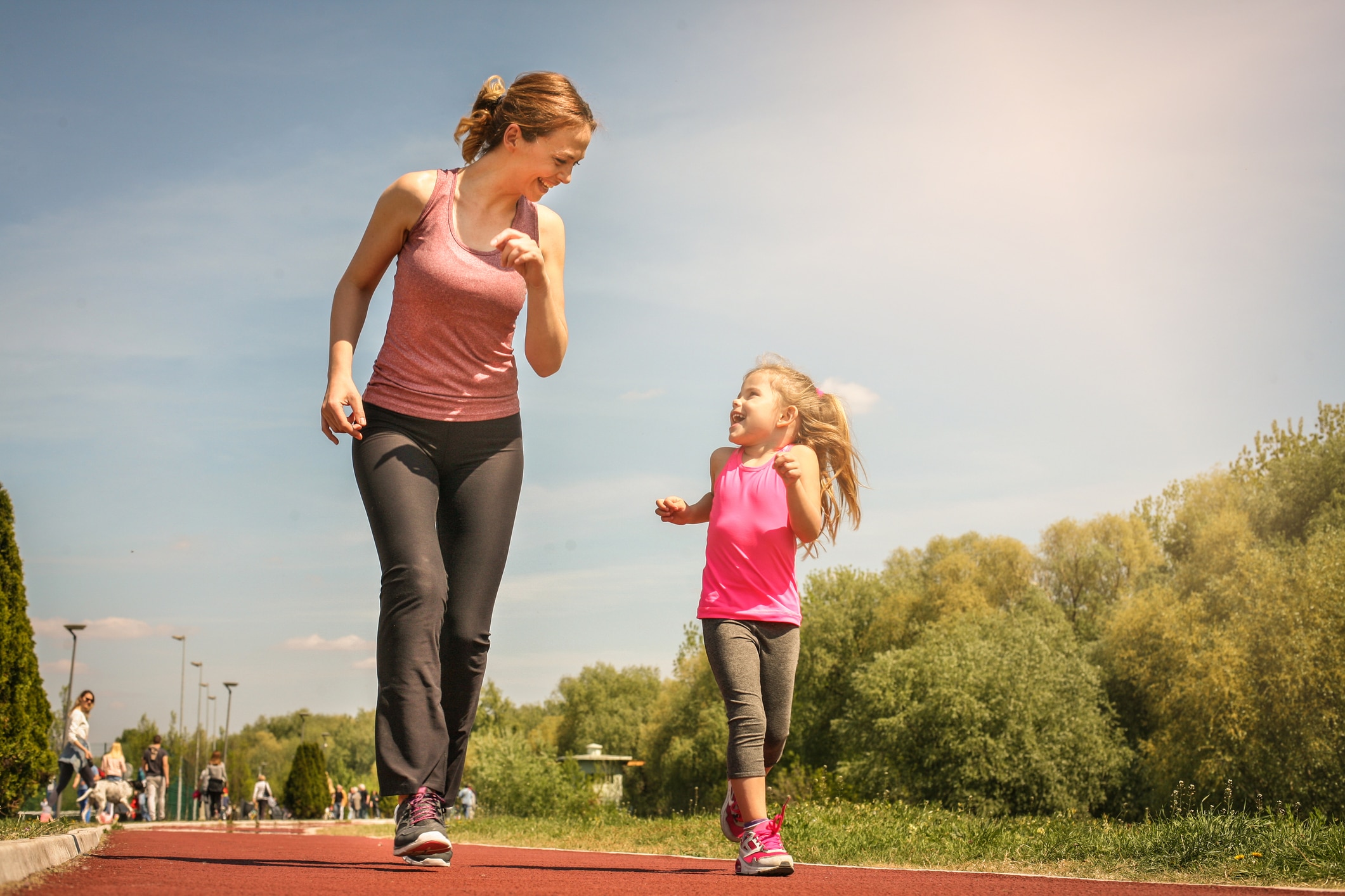 Woman and child looking at each other and running together at a park