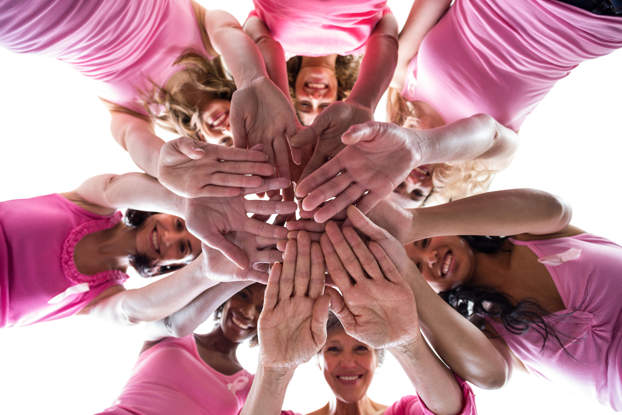 Women in pink outfits joining in a circle for breast cancer awareness