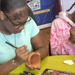 Two participants of UofL Health's Community Engagement Initiative for Gun Violence Prevention decorating clay pots as part of art therapy.
