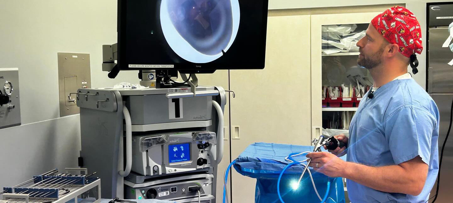 UofL Health neurosurgeon Dr. David Freeman studies an operating room monitor while holding using Elliquence endoscopic spine surgery equipment.